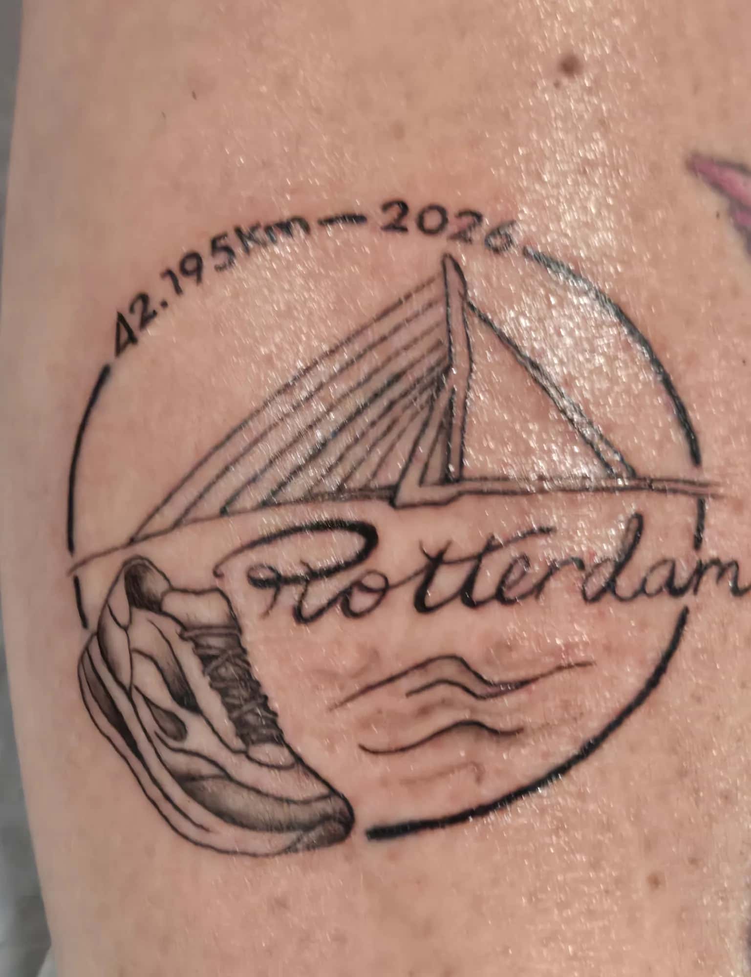 Fineline tattoo van het Rotterdam Marathon-embleem met Erasmusbrug en hardloopschoen