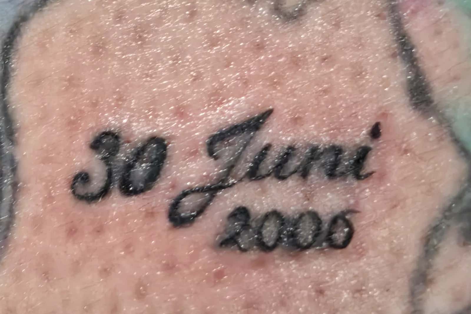 Handgeschreven script-tattoo van een datum, gezet bij GlowLine